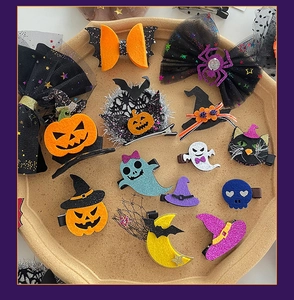 Close-up of Halloween hair clips with felt pumpkin, ghost, and bat designs on a wooden tray