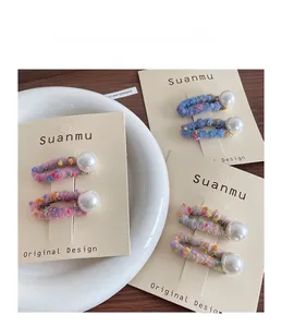 Detailed view of handmade felt hair clips with large white pearls in soft pastel colors
