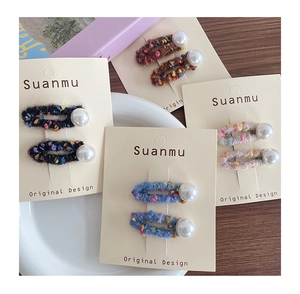 Detailed close-up of handmade felt hair clips with large white pearls on a display card