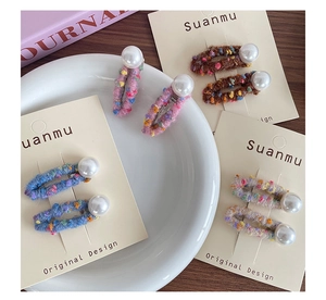 Close-up of colorful handmade wool yarn hair clips with large white pearl accents