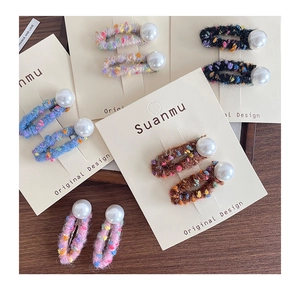 Detail of colorful knitted felt hair clips with large pearl accents on display cards