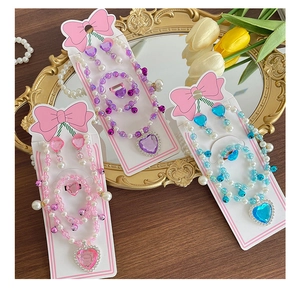 Close-up of children's jewelry set with heart gemstones and pearls on a mirror