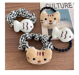 Détail d'élastiques à cheveux en peluche chat et poisson sur fond en bois avec journal