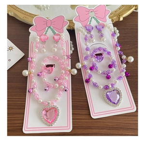 Detail of pink and purple beaded jewelry sets with heart pendants and tiny bells