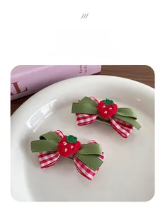 Détail de pinces à cheveux en ruban à carreaux rouges avec breloques fraises