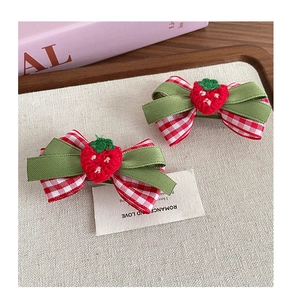Détail de barrettes nœuds à carreaux rouges avec fraise tricotée pour cheveux fille