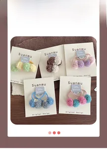 Detail of colorful plush ball hair ties on a display card showing soft texture and colors