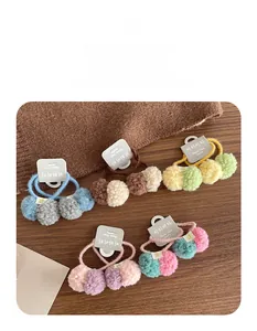 Close-up of colorful plush pompom hair ties set on a rustic wooden background