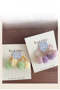Detailed view of soft colorful plush pom pom hair ties on white card packaging