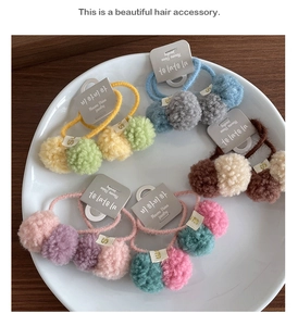 Detail of high-elasticity hair ties with soft colorful pom-poms on premium display cards