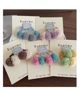 Detailed close-up of soft colorful plush ball hair ties for girls on wooden surface