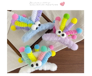 Détail de pinces à cheveux en peluche avec torsades arc-en-ciel et grands yeux rigolos