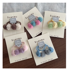 Detail of five colorful plush pompom hair ties set on display cards for girls