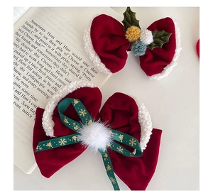 Détail de nœuds de Noël en velours rouge avec pompons blancs et feuilles de houx