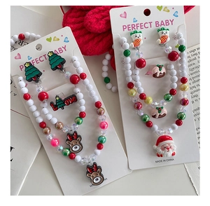 Close-up of kids Christmas jewelry set with Santa and reindeer beads on red background