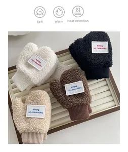 Close-up of four colors of fleece mittens with letter patches in a display tray