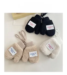 Detailed view of plush fleece kids mittens in black, beige, and white with hanging strings