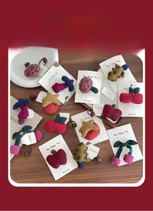 Detail of plush fruit hair clips and elastic bands in corduroy material on a wooden table
