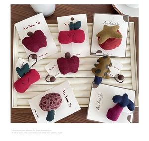 Detail showing forest style fruit and tree plush hair clips on a white display tray