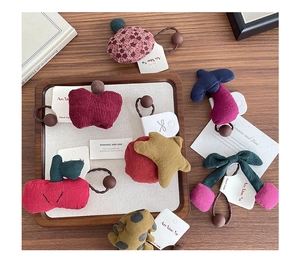Detailed close-up of handmade plush fruit hair ties with apple and cherry designs
