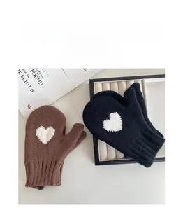 Detail of knitted winter mittens with white heart patterns and hanging neck strap