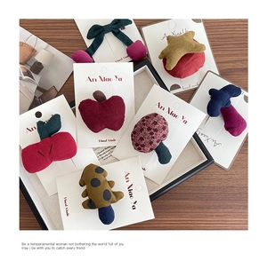 Detail of handmade corduroy apple and mushroom hair clips on display card