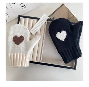Close-up of knit winter mittens for kids featuring small heart patterns and ribbed cuffs