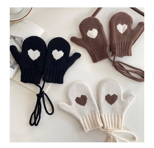 Close-up of thick knitted mittens with heart patterns in black, brown, and beige colors