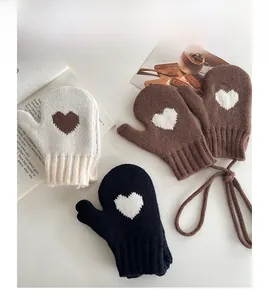 Detail of knitted mittens with heart pattern and anti-lost neck string for children
