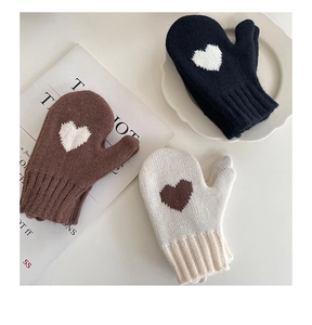 Detailed view of three pairs of thick knitted winter mittens with large heart patterns