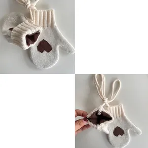 White knitted kids mittens with brown heart pattern and neck strap for winter warmth