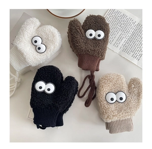 Détail de moufles pelucheuses en laine d'agneau avec yeux de dessin animé et poignets