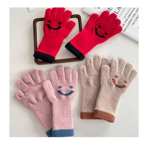 Detailed view of three pairs of soft knitted gloves in red, pink, and beige with smiley patterns