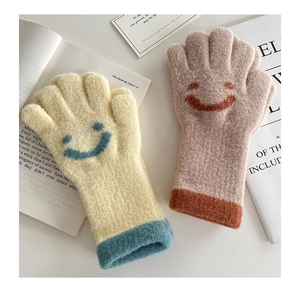 Detail of warm knitted kids gloves with cute smiley faces and soft plush texture