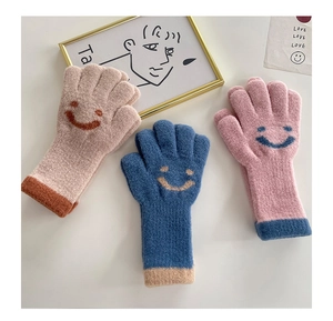 Three pairs of cute knitted kids gloves with smiley patterns in beige, navy, and pink