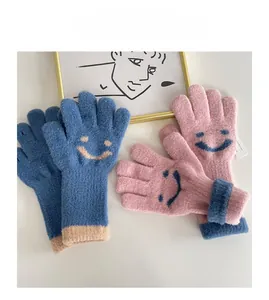 Close-up of warm knitted fingerless gloves with a cute smiling face pattern