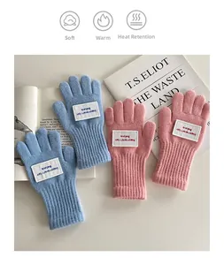 Detail von warmen Strickhandschuhen für Kinder mit Rippbündchen und gewebtem Aufnäher
