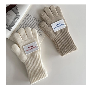 Nahaufnahme von Strickhandschuhen ohne Finger mit Rippbündchen und Deko-Aufnäher