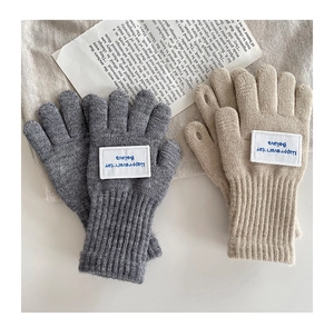 Nahaufnahme warmer Strickhandschuhe mit Stickerei in Grau und Beige für Kinder im Winter