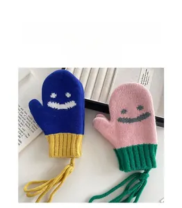 Dettaglio di caldi guanti in maglia per bambini con faccine sorridenti e cordino