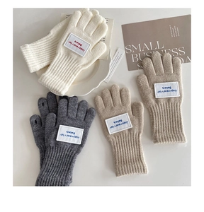 Detail der gestrickten fingerlosen Winterhandschuhe mit Rippbündchen und Stickerei Motiv