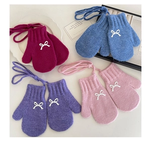 Detail view of colorful knitted toddler mittens with 3D bows and neck strings