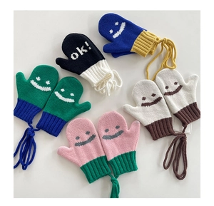 Dettaglio di muffole in maglia per bambini con faccina sorridente e cordino anti-smarrimento