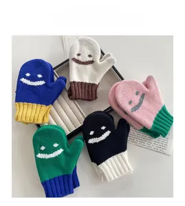 Dettaglio dei caldi guanti in maglia per bambini con faccina e trame colorate