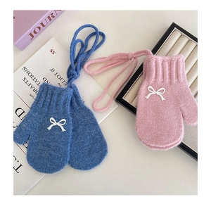 Detail of soft knit children's gloves with bow accents and neck strap for winter