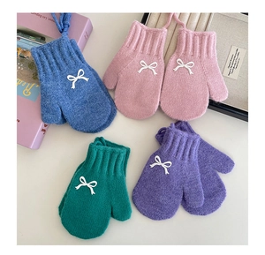 Flat lay of four colorful knit mittens with 3D white bows and hanging neck cords