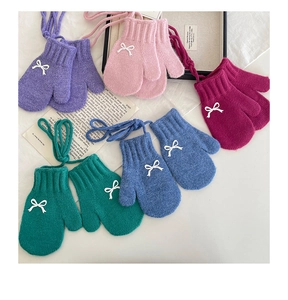 Detail of colorful knitted winter mittens with bows and neck strings for young girls