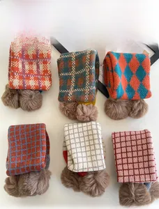 Detailansicht gestrickter Kinderschals mit Karomuster und flauschigen braunen Bommeln