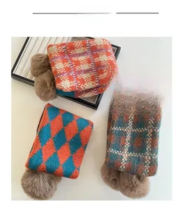 Detailansicht von gestrickten Karo-Schals mit weichen Pompons in drei verschiedenen Farbmustern