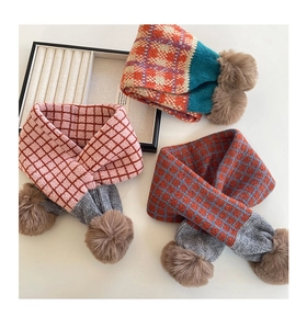 Detailansicht bunter karierter Strickschals für Kinder mit flauschigen Kunstfell-Pompons